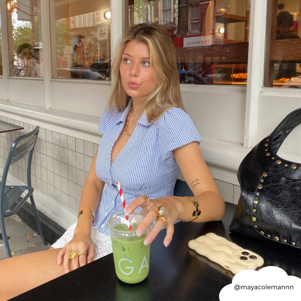 Butter yellow Coconut Lane 3D Bubble phone case on café table next to woman with blonde hair holding a green drink.