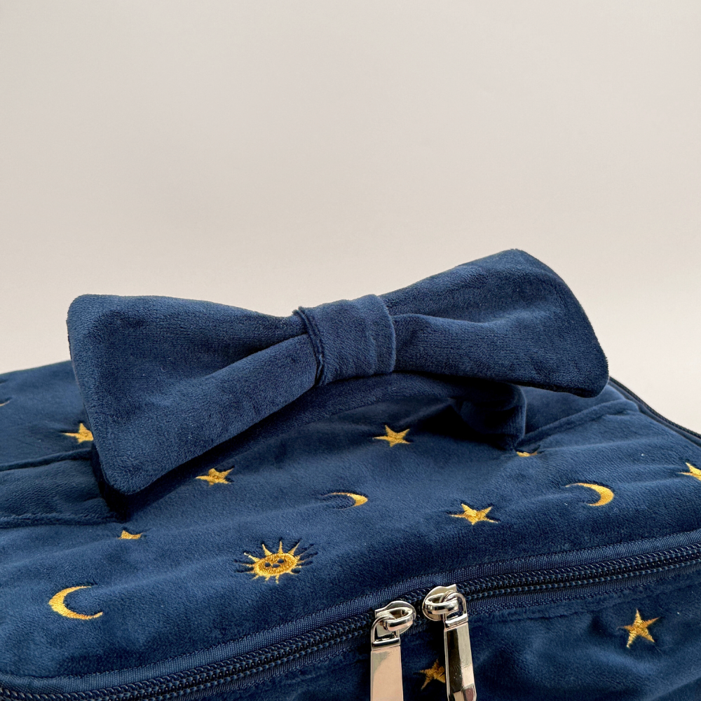 Blue velvet travel vanity case with embroidered stars, moons, and a matching bow.