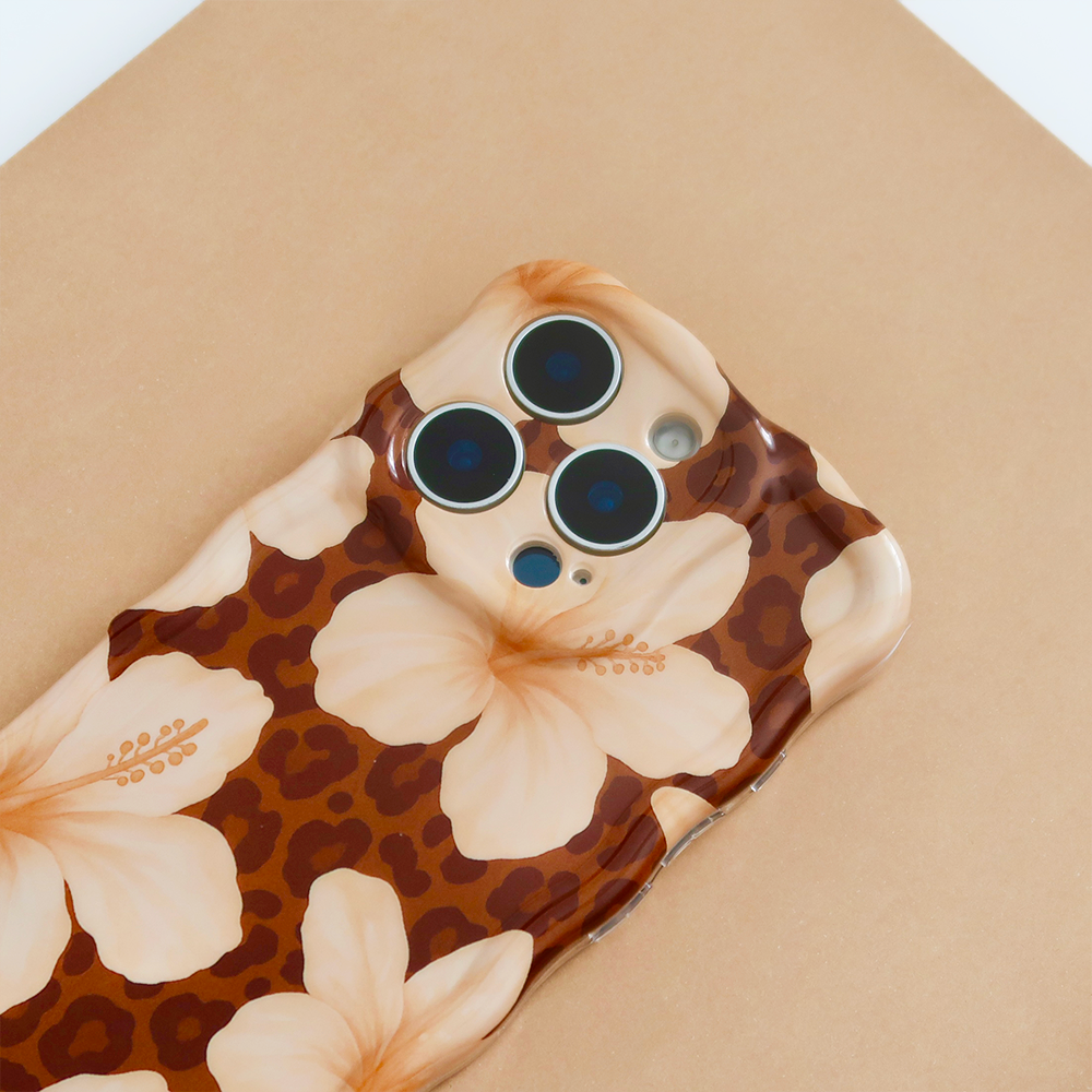 A white iPhone case decorated with small bows and pearls is displayed on a beige background surrounded by scattered pearls, white bows, and star-shaped confetti.