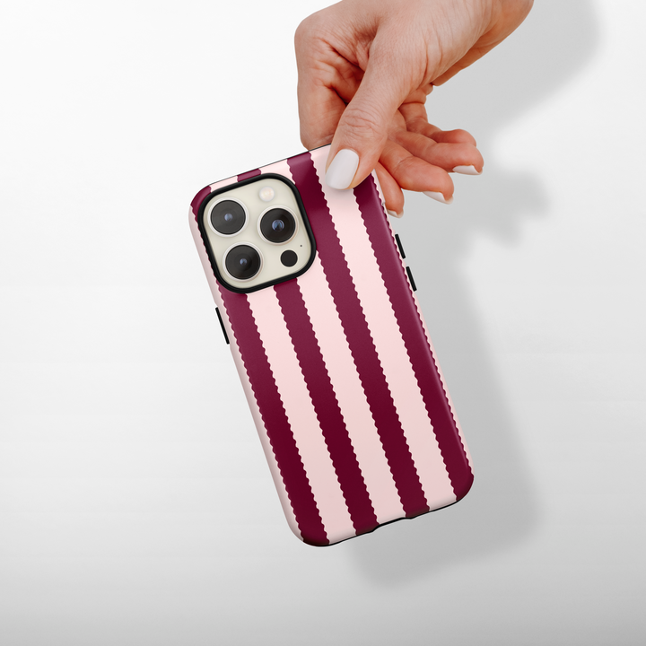 Hand holding phone with Blushberry Scallop Stripes Coconut Lane Tough MagSafe case, shown on a white background.