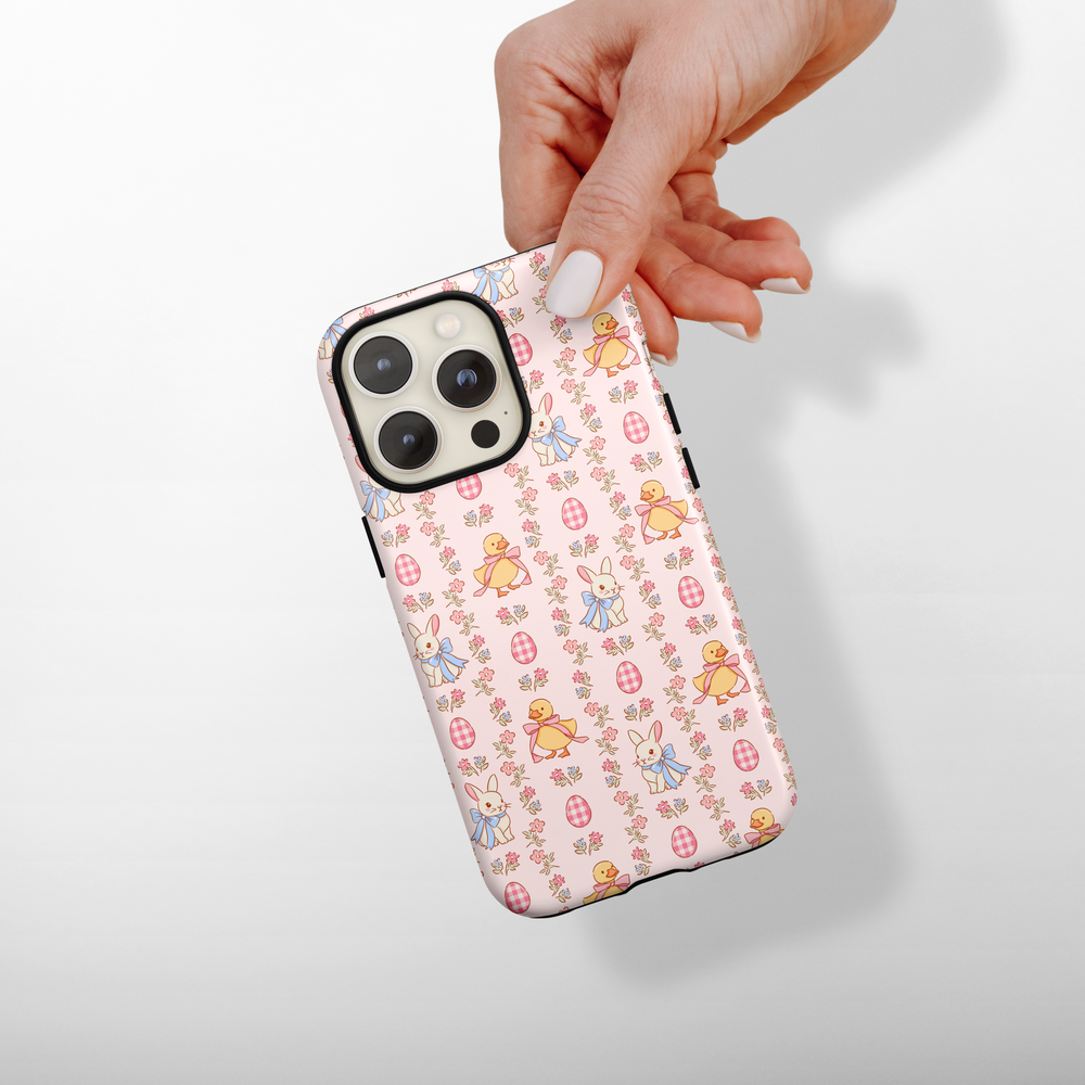 Phone case with bunnies and chick pattern held by a hand on a light background