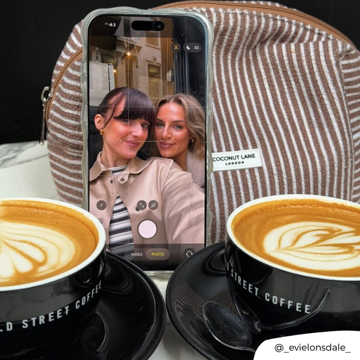 Girls taking selfie with chestnut stripes makeup bag in the background