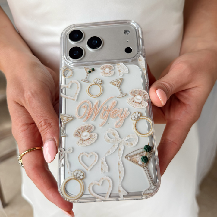 Phone case with 'Wifey' text and wedding ring designs held by hands.