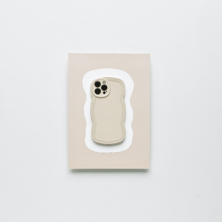 A minimalist, lightweight NAKD Curvy Phone Case - Vanilla by Coconut Lane in a neutral beige color is placed on a matching beige rectangular card against a white background. The case has cutouts for the camera and buttons, and its edges are subtly contoured for highly protective functionality.