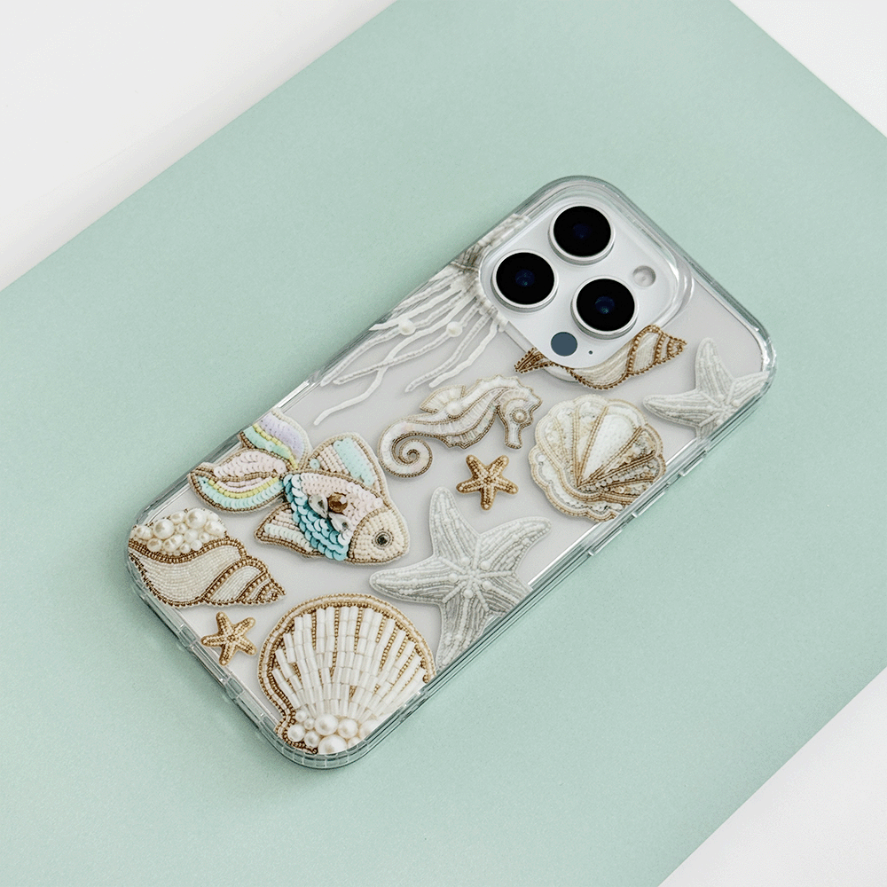 Clear phone case in mint green with embroidered seashell, fish, and starfish motifs.