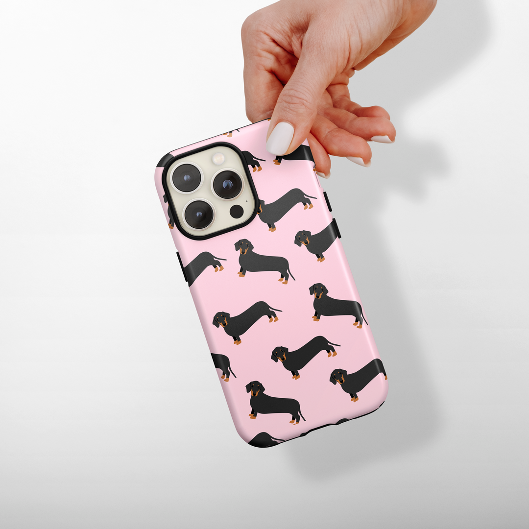 Phone case with dachshund pattern held by a hand on a light background