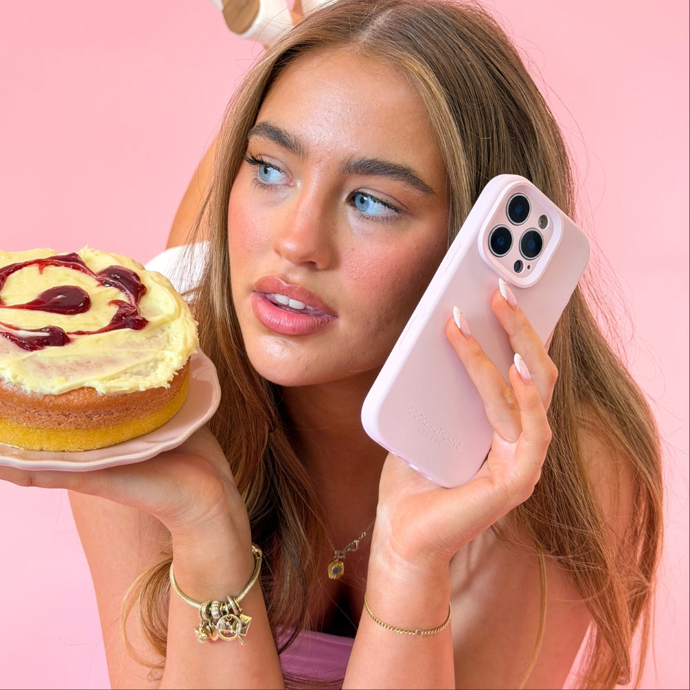 Woman holding a pink phone case and a raspberry ripple cake against a pink background