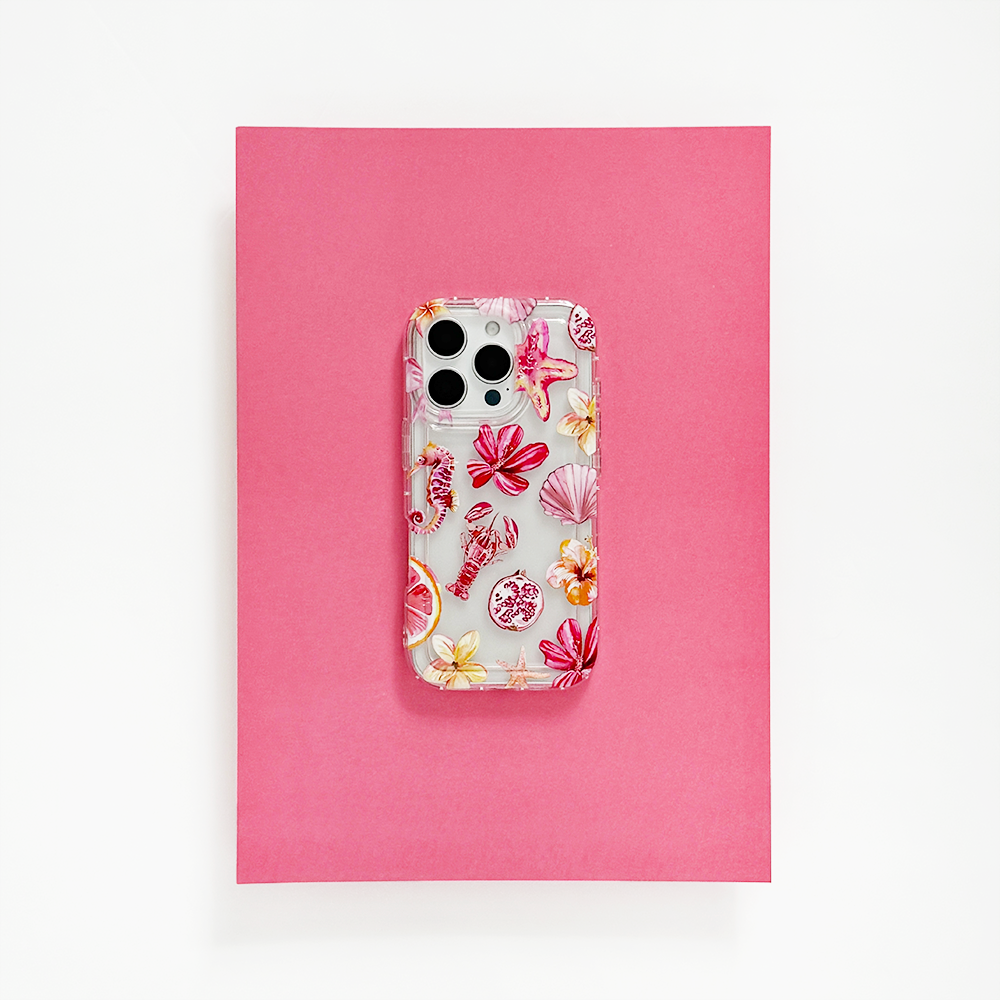 Clear Coconut Lane Rosé Coast phone case on a smartphone, resting on a bright pink sheet with white background.
