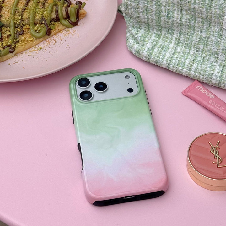 Strawberry matcha phone case on a pink surface next to some pink makeup products.