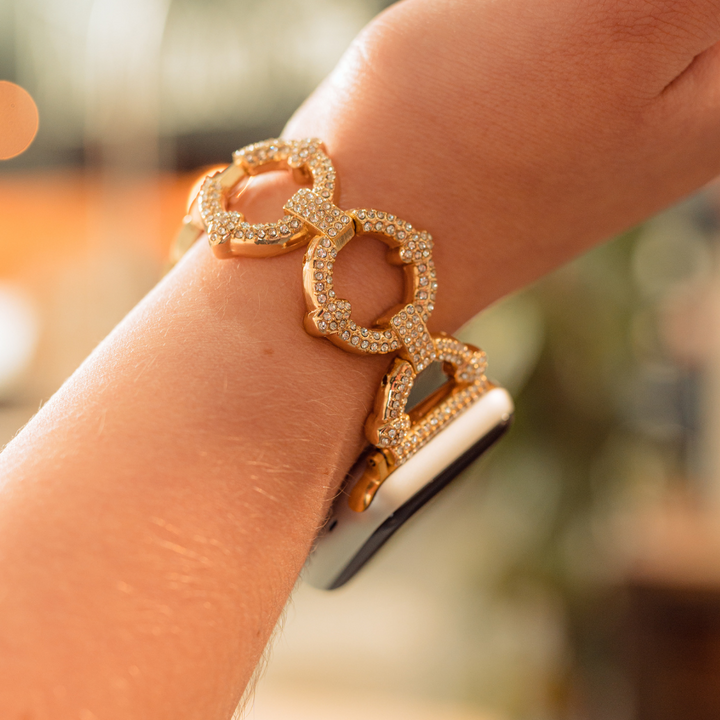 A close-up of a person's wrist features the luxurious Diamante Bracelet Apple Watch Strap by Coconut Lane, adorned with sparkling gems. This exquisite piece blends sophisticated elegance with modern technology. The slightly blurred background enhances the focus on this stunning jewelry and its seamless integration with the latest Apple Watch models.