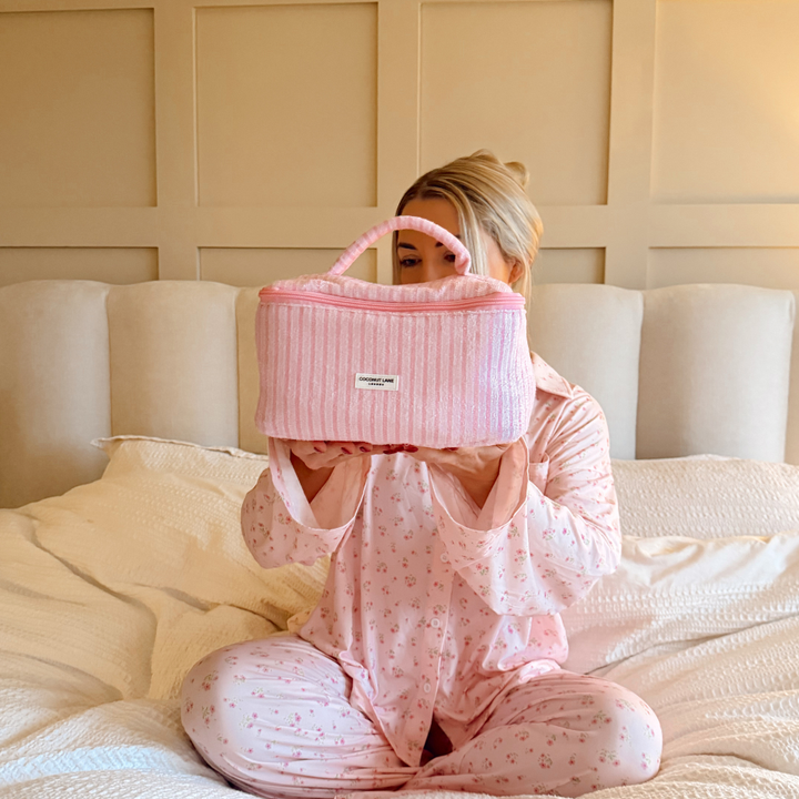 Girl in bed holding Powder Stripes Vanity Case wearing pink pyjamas