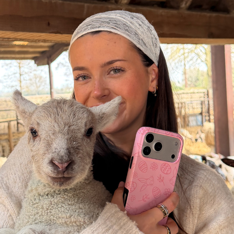 Girl smiling holding lamb and blush bunny tough phone case in hand
